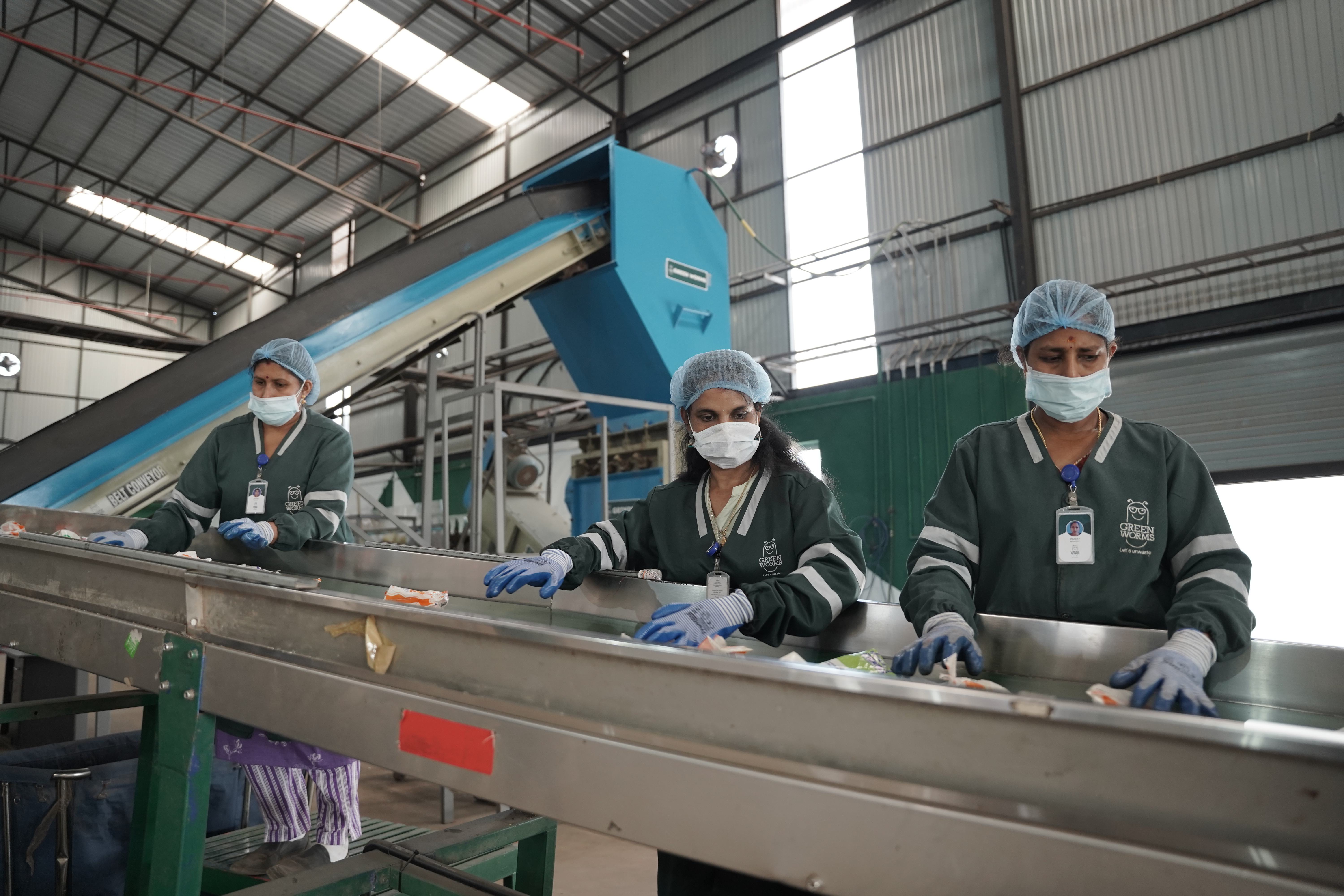 Workers sorting waste on a conveyor belt at a facility
