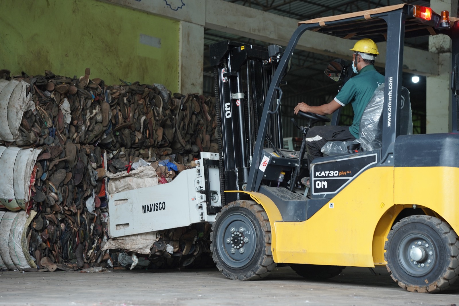 Forklift moving baled waste at a recycling facility